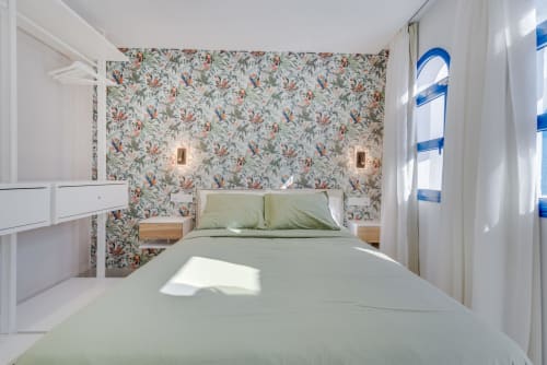 Dormitorio luminoso en Bungalow Flor del Almendro, Maspalomas con papel floral, ropa de cama verde, mesitas de madera y jardín