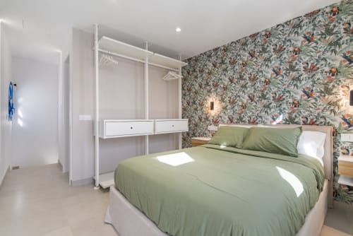 Dormitorio moderno en Bungalow Flor del Almendro, Maspalomas con ropa de cama verde, papel tapiz floral y armario blanco.