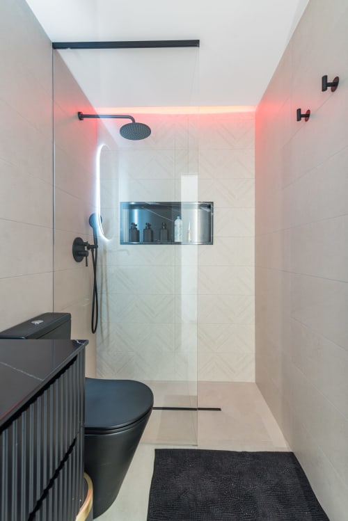 Baño moderno en Bungalow Flor del Almendro, Maspalomas con accesorios negros, iluminación neón y ducha tipo walk-in