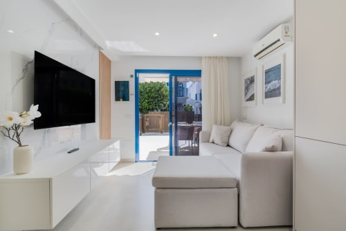 Luminosa sala de estar en Bungalow Flor del Almendro, Maspalomas, con sofá, TV de pantalla plana y vista al jardín
