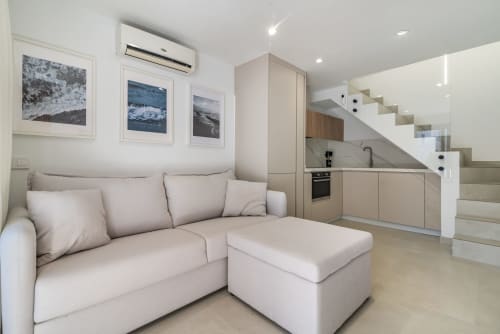 Moderno salón con sofá beige, otomana y cocina abierta en Maspalomas, Gran Canaria