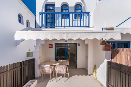 Terraza exterior del Bungalow Flor del Almendro en Maspalomas con detalles azules, mesa de comedor, toldo blanco y vistas al océano