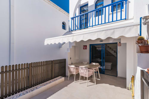 Terraza del bungalow Flor del Almendro en Maspalomas con comedor, barandilla azul y entrada privada