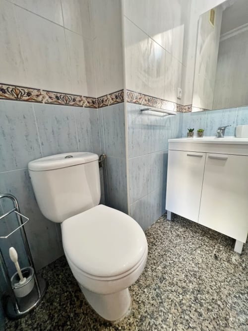 Baño moderno en apartamento de Fuengirola con inodoro blanco, lavamanos y cenefa de azulejos decorativos