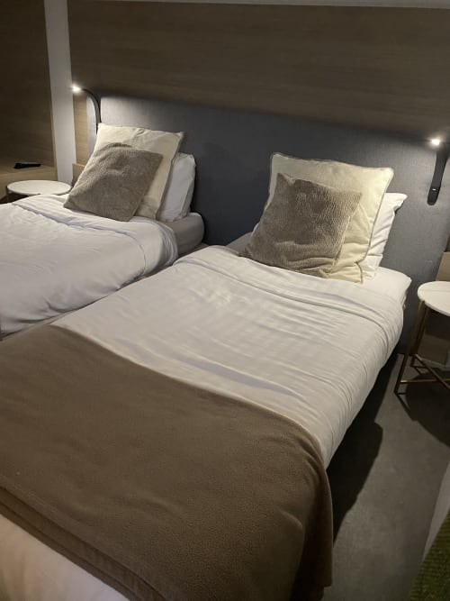 Deux lits jumeaux aux draps blancs et oreillers gris dans le Studio twin n°1 de l'hôtel Cosyade, Bourbourg
