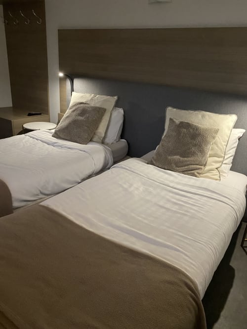 Lits jumeaux avec draps blancs et coussins gris à la Cosyade Studio à Bourbourg, appartement avec vue sur jardin