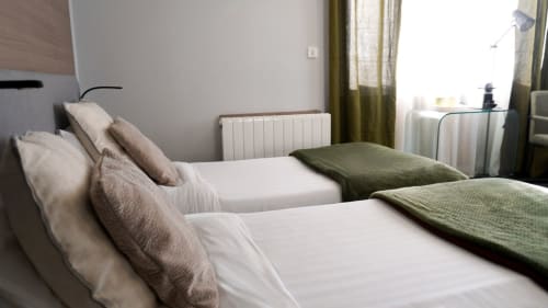 Studio chambre twin à l'hôtel Cosyade à Bourbourg avec lits blancs, oreillers verts, radiateur et vue sur le jardin