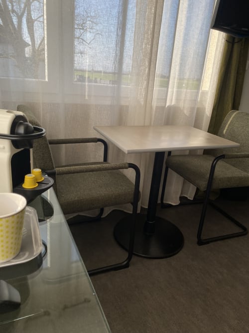 Coin repas moderne avec table, chaises olive et rideaux voilages dans le studio de l'hôtel Cosyade à Bourbourg