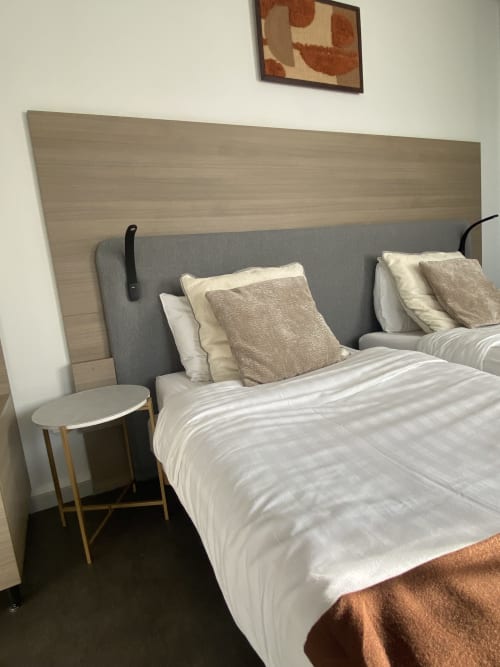 Chambre twin studio à l'hôtel Cosyade à Bourbourg avec tête de lit capitonnée grise, literie blanche et table de nuit