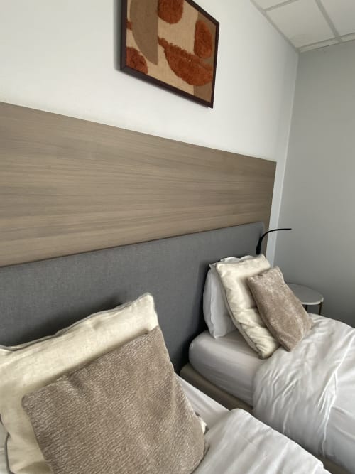 Lits jumeaux modernes avec tête de lit grise et couvertures beige au studio de l'hôtel Cosyade à Bourbourg, France