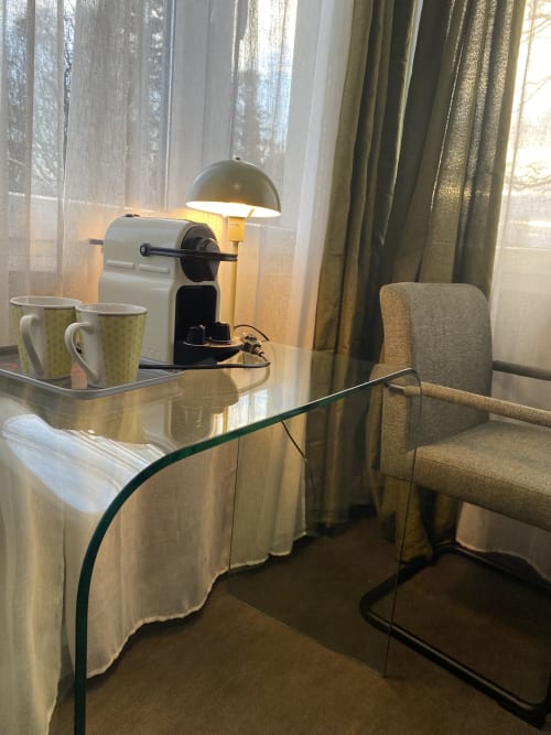 Chambre twin studio à l'hôtel Cosyade avec bureau vitré, cafetière, lampe et chaise face à la fenêtre donnant sur le jardin