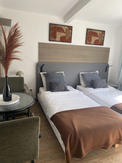 Chambre standard avec lits jumeaux, tête de lit grise et vue sur jardin à l'hôtel Cosyade à Bourbourg