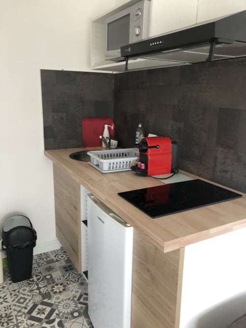 Kitchenette moderne en Studio supérieur à l'hôtel Cosyade avec machine à café rouge, plaque de cuisson noire et crédence foncée