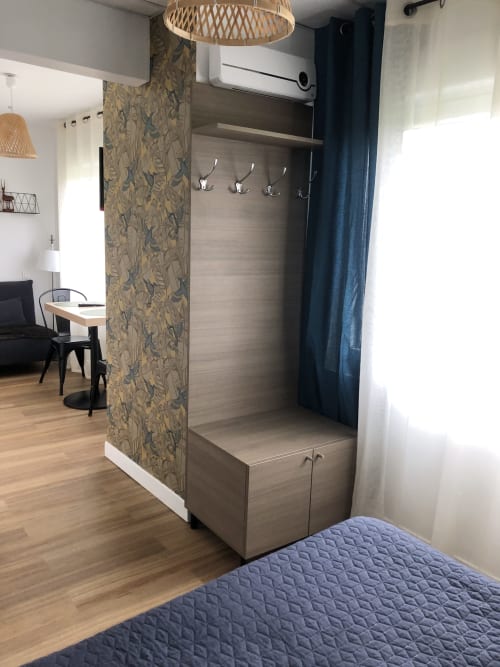 Entrée moderne du studio Cosyade à Bourbourg avec meuble de rangement bois, patères et luminaire suspendu tressé