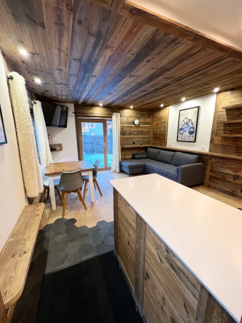 Modern wood-paneled apartment interior at Chez Francine with kitchen, dining area, sofa, and garden view access