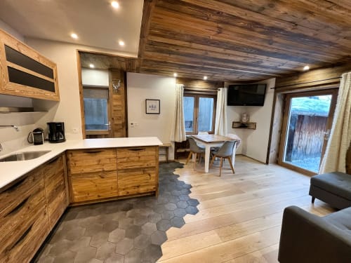 Modern apartment kitchen and living area with wooden beams, dining table, and garden views in Chez Francine,