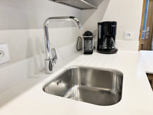 Modern kitchenette with stainless steel sink, chrome faucet, and coffee makers at Chez Francine apartment in