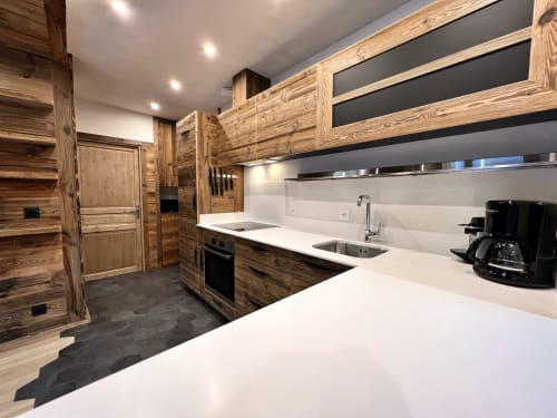 Modern kitchen in Chez Francine apartment with wooden cabinetry, white countertops, stainless steel sink and appliances
