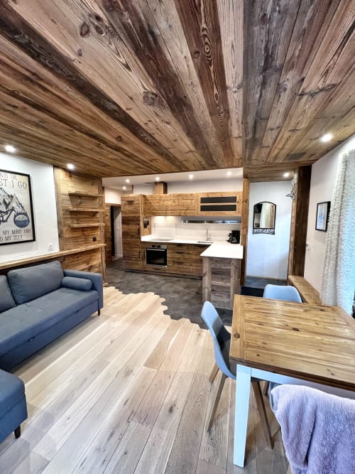 Modern wood-accented apartment interior at Chez Francine with kitchen, dining area, sofa, and wooden ceiling