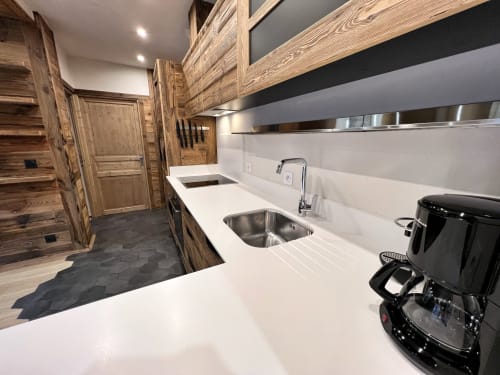Modern galley kitchen with white countertop, stainless steel sink, and wooden cabinetry in Appartement Alba, Chez Francine