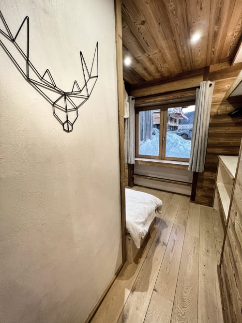 Modern bedroom with wooden beamed ceiling, line art deer decal, wood flooring, and snowy mountain view at Chez Francine