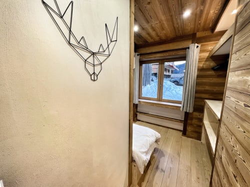 Cozy bedroom at Chez Francine apartment with wooden beams, geometric wall art, and snowy alpine view in