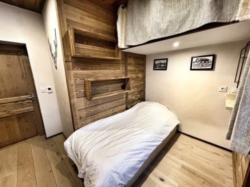 Cozy bedroom in Chez Francine apartment with wooden furnishings and white bedding in Notre-Dame-de-Bellecombe