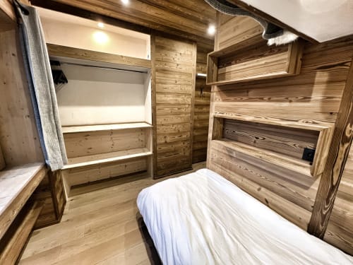Wooden bedroom in Chez Francine apartment with bunk beds, shelving, and rustic alpine decor in Notre-Dame-de-Bellecombe