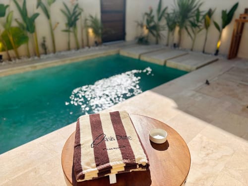 Oasis Dune Villas villa pool with striped towel, white flowers, and tropical palms in Lombok, Indonesia