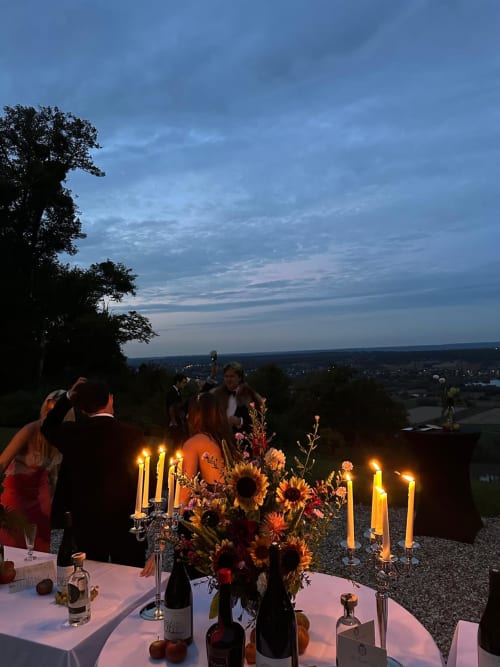 Sunset dinner at Château Du Landin with lit candles, floral arrangements, and countryside valley views