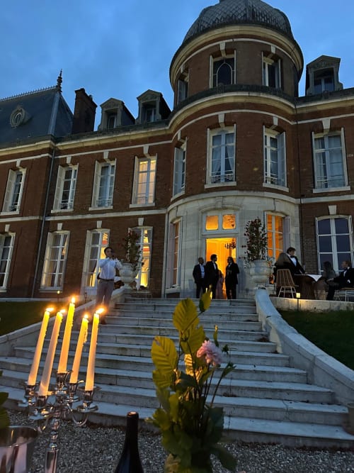 Château Du Landin evening exterior with candlelit entrance, guests mingling, illuminated windows and mansard roof