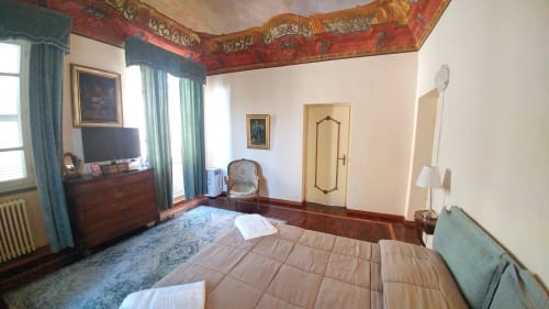 Elegant bedroom at Bresbot B&B in Bressana with period ceiling, hardwood floors, garden view, TV, and private bath