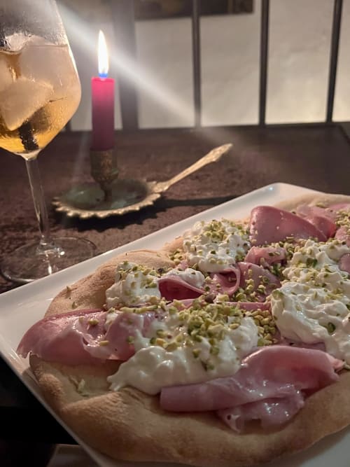 Elegante dolce presentato con meringa rosa e pistacchio presso l'Agritusmo Stecadò, Dolceacqua, in atmosfera di cena a lume di candela