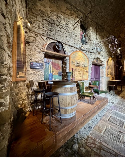 Interno di enoteca medievale presso l'Agritismo Stecadò, Dolceacqua, con muri in pietra, bancone in botte e atmosfera rustica