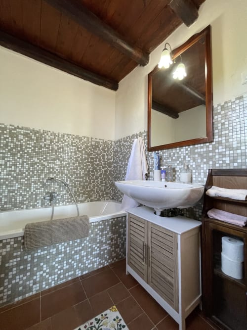 Bagno moderno presso Mater Familias Oasis a Siracusa con pareti in mosaico, lavabo bianco e vasca da bagno