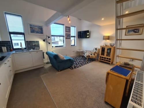 Modern studio apartment at 2 Doves Holiday Property in Exeter with blue armchair, kitchenette, and wooden furniture