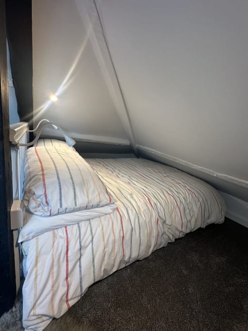 Cozy bedroom at 2 Doves Holiday Property in Exeter with striped bedding and sloped ceiling