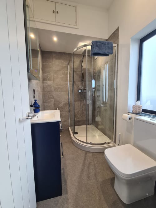 Modern ensuite bathroom at 2 Doves Holiday Property in Exeter featuring shower cubicle, toilet and vanity sink.