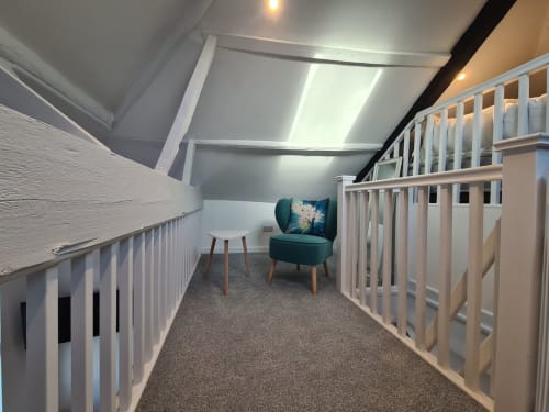Modern attic nursery at 2 Doves Holiday Property, Exeter, with two white cribs and teal accent chair
