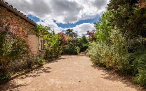 Allée de gravier ombragée bordée de verdure menant à l'entrée de la villa Casa de la huerta à Millau, France