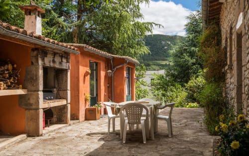 Terrasse avec chaises blanches surplombant la vallée de Millau, villa orange Casa de la huerta aux détails en pierre