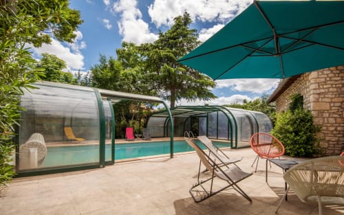 Piscine privée avec abri rétractable, chaises longues et parasol turquoise à la villa Casa de la huerta à Millau