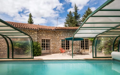 Piscine turquoise avec patio vitré, villa en pierre et chaises longues à Millau, France