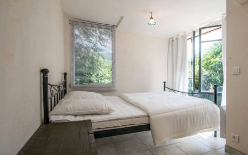 Chambre lumineuse avec lits jumeaux, têtes de lit métalliques, grandes fenêtres à volets et vue sur la campagne à Casa de la huerta villa