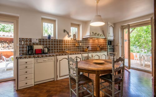 Spacieuse cuisine et salle à manger de villa avec dosseret en carrelage décoratif, table en bois et vue sur le jardin à Millau