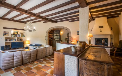 Spacieux salon de villa avec poutres en bois apparent, cheminée, îlot de cuisine et portail voûté à Millau
