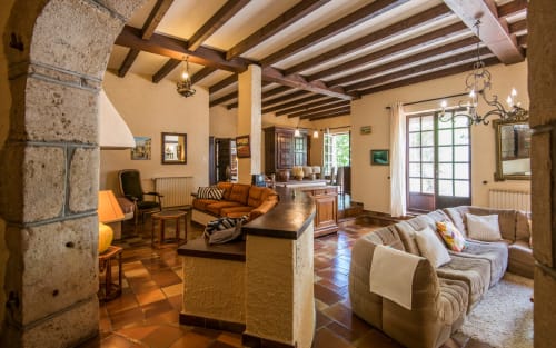Spacieux salon de la villa Casa de la huerta à Millau, avec poutres apparentes, carrelage en terre cuite et mobilier traditionnel