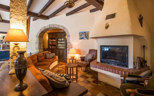 Spacieux salon de villa à Millau avec cheminée, sièges orangés, poutres apparentes et TV