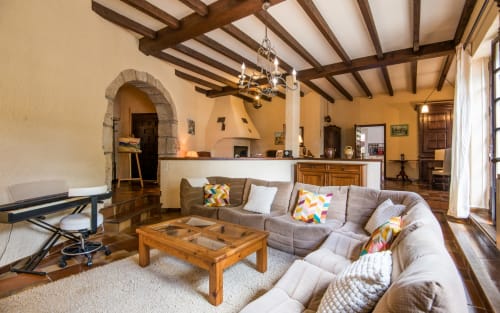 Spacieux séjour de la villa Casa de la huerta à Millau avec plafond à poutres, canapé gris, table en bois et équipements modernes
