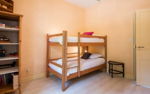 Lit superposé en bois avec literie blanche dans une chambre lumineuse de villa à Millau, équipée d'étagères intégrées et de meubles en bois